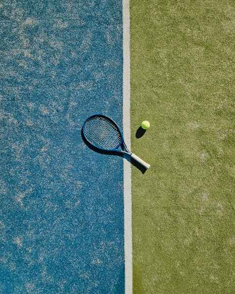Tennisschläger und Ball an der weißen Platzlinie